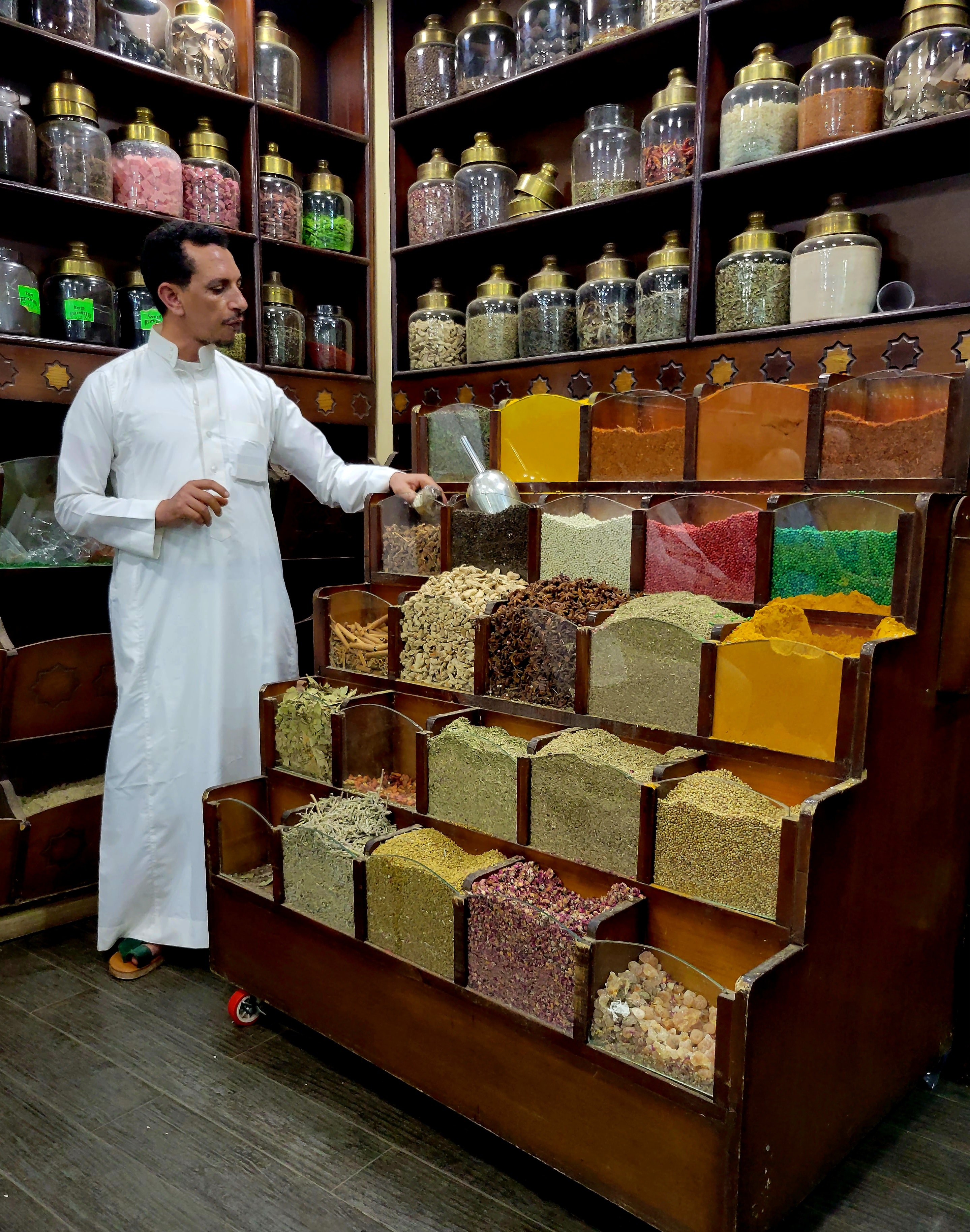 A spice vendor standing beside a stunning display of colorful spices and herbs in an Egyptian market