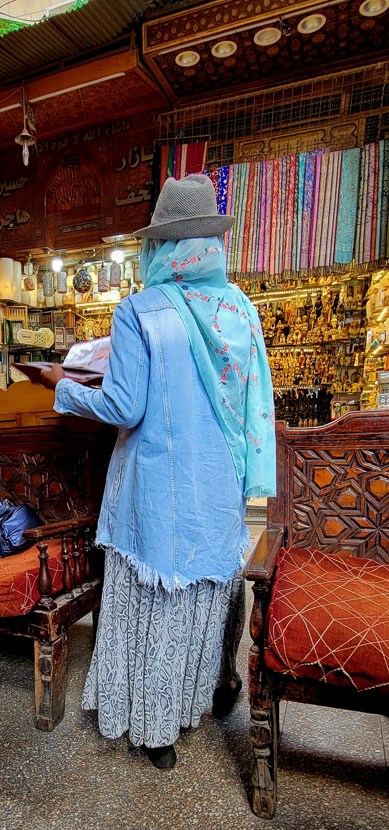 A woman browsing colorful textiles and souvenirs in the ornate wooden stalls of Khan el-Khalili bazaar in Cairo