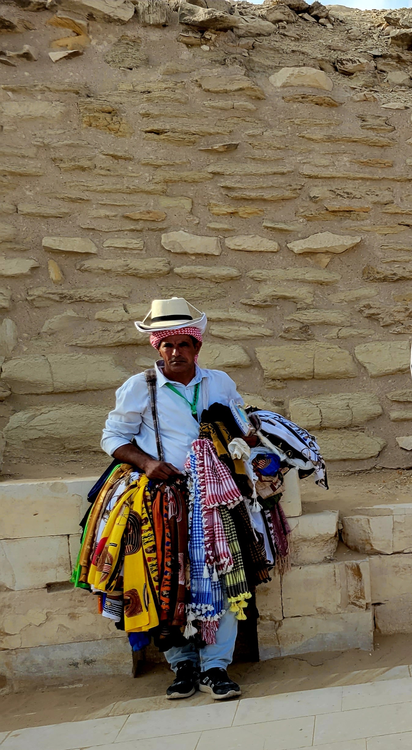A man selling colorful scarves and textiles near the pyramids