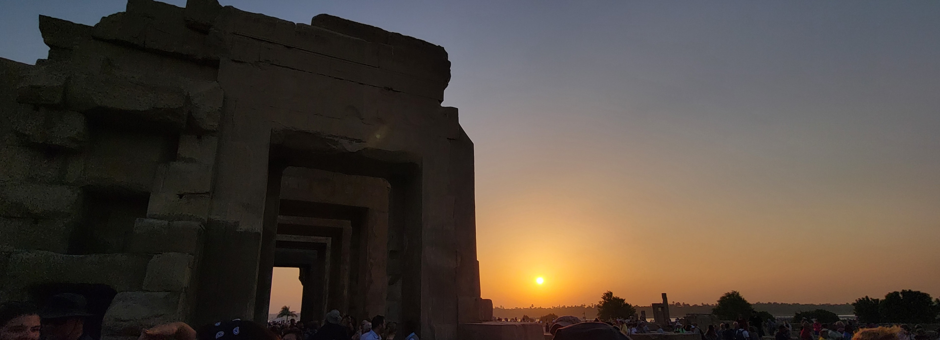 The sun setting through the ancient stone doorways of the Temple of Kom Ombo